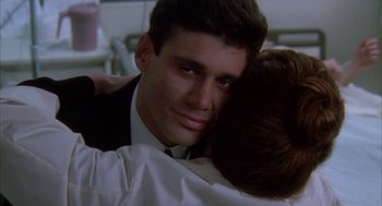 Movie still from “Raising Cain” (1992), directed by Brian De Palma – A man and a woman hugging each other in front of a window; Close Up shot, Over the shoulder angle