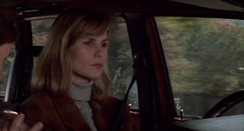 Movie still from “Raising Cain” (1992), directed by Brian De Palma – A woman sitting in the driver's seat of a car; Close Up shot, Over the shoulder angle