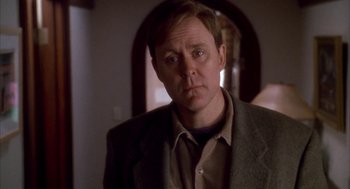 Movie still from “Raising Cain” (1992), directed by Brian De Palma – A person wearing a suit and tie; Close Up shot, Over the shoulder angle