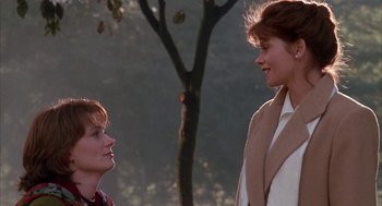 Movie still from “Raising Cain” (1992), directed by Brian De Palma – Two people standing next to each other near a tree; Medium shot, Over the shoulder angle