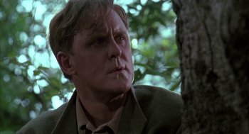 Movie still from “Raising Cain” (1992), directed by Brian De Palma – A person wearing a jacket near a tree; Close Up shot, Low angle