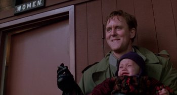 Movie still from “Raising Cain” (1992), directed by Brian De Palma – A man holding a baby in his arms and smiling for the camera; Close Up shot, Low angle
