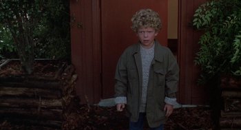 Movie still from “Raising Cain” (1992), directed by Brian De Palma – A young boy standing in front of a door way; Medium shot, High angle