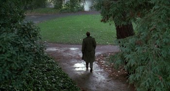 Movie still from “Raising Cain” (1992), directed by Brian De Palma – A man in a green coat is standing in a park; Extreme Wide shot, High angle