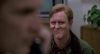 Movie still from “Raising Cain” (1992), directed by Brian De Palma – A person wearing a jacket with a smirking face; Close Up shot, Over the shoulder angle