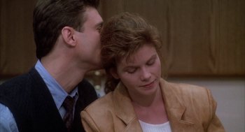 Movie still from “Raising Cain” (1992), directed by Brian De Palma – A man whispers into a woman's ear; Close Up shot, Over the shoulder angle