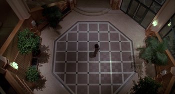 Movie still from “Raising Cain” (1992), directed by Brian De Palma – A person is standing in the middle of a floor; Extreme Wide shot, Overhead angle