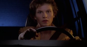 Movie still from “Raising Cain” (1992), directed by Brian De Palma – A woman sitting in the driver's seat of a car; Close Up shot, Low angle