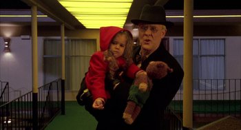 Movie still from “Raising Cain” (1992), directed by Brian De Palma – An older man holding a young girl and a teddy bear; Medium shot, Low angle