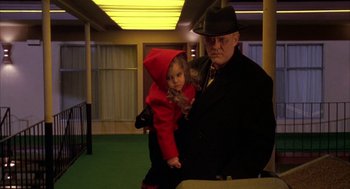Movie still from “Raising Cain” (1992), directed by Brian De Palma – An older man holding a young girl in a red coat; Medium shot, High angle