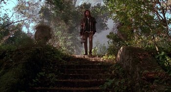 Movie still from “Raising Cain” (1992), directed by Brian De Palma – A man standing on a set of stairs in the woods; Wide shot, Low angle