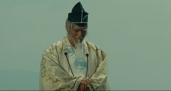 Movie still from “Ran” (1985), directed by Akira Kurosawa – An older man wearing a hat and a robe; Medium shot, Low angle