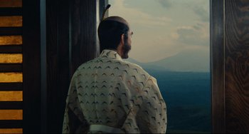 Movie still from “Ran” (1985), directed by Akira Kurosawa – A man with a beard is looking out of a window; Medium shot, Over the shoulder angle