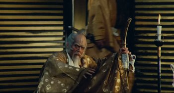 Movie still from “Ran” (1985), directed by Akira Kurosawa – An old man dressed in a gold and black outfit; Medium shot, Low angle