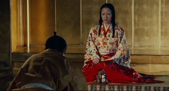 Movie still from “Ran” (1985), directed by Akira Kurosawa – A person sitting on a chair in front of another person; Medium shot, High angle