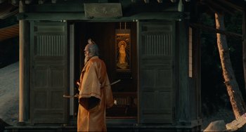 Movie still from “Ran” (1985), directed by Akira Kurosawa – An old man dressed in a kimono and holding a sword; Wide shot, Low angle