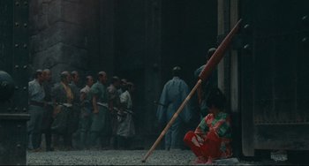 Movie still from “Ran” (1985), directed by Akira Kurosawa – A group of people standing around a building; Wide shot, High angle