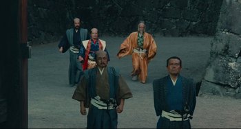 Movie still from “Ran” (1985), directed by Akira Kurosawa – A group of men dressed in traditional japanese garb; Wide shot, Low angle