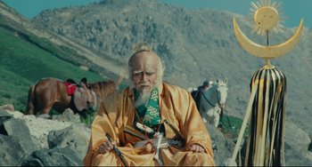 Movie still from “Ran” (1985), directed by Akira Kurosawa – An old man sitting on top of a mountain with horses; Medium shot, Low angle