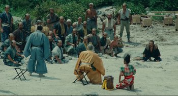 Movie still from “Ran” (1985), directed by Akira Kurosawa – A group of people sitting on the ground; Extreme Wide shot, High angle