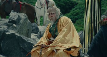 Movie still from “Ran” (1985), directed by Akira Kurosawa – An old man sitting on a rock near some horses; Medium shot, Low angle