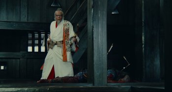 Movie still from “Ran” (1985), directed by Akira Kurosawa – An old man dressed in a kimono standing next to a dead body; Wide shot, Low angle