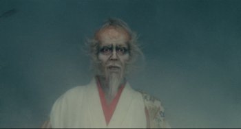 Movie still from “Ran” (1985), directed by Akira Kurosawa – An old man with long white hair wearing a white robe; Close Up shot, Low angle