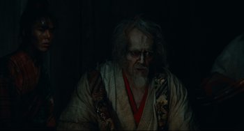 Movie still from “Ran” (1985), directed by Akira Kurosawa – An old man with long white hair wearing a robe; Medium shot, Over the shoulder angle