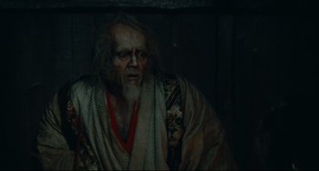 Movie still from “Ran” (1985), directed by Akira Kurosawa – An old man with long hair and a beard wearing a robe; Medium shot, High angle