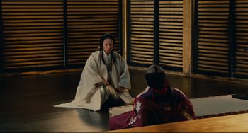 Movie still from “Ran” (1985), directed by Akira Kurosawa – Two women in traditional japanese garb sitting on the floor; Wide shot, High angle