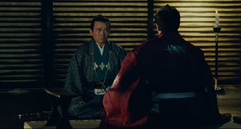 Movie still from “Ran” (1985), directed by Akira Kurosawa – A man in a kimono sitting in front of another man; Medium shot, Over the shoulder angle