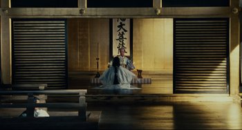 Movie still from “Ran” (1985), directed by Akira Kurosawa – A man sitting on a chair in a room; Extreme Wide shot, High angle