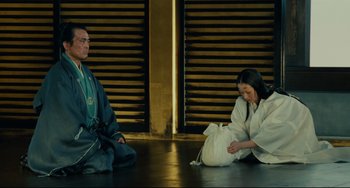 Movie still from “Ran” (1985), directed by Akira Kurosawa – A man and a woman sitting on the ground; Wide shot, Low angle