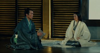 Movie still from “Ran” (1985), directed by Akira Kurosawa – A man and a woman sitting on the ground; Wide shot, High angle