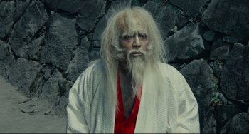 Movie still from “Ran” (1985), directed by Akira Kurosawa – A man with long white hair and a white beard; Close Up shot, Low angle
