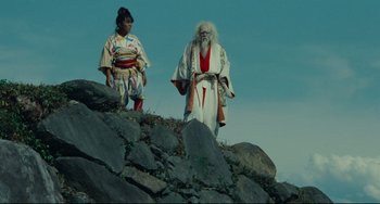 Movie still from “Ran” (1985), directed by Akira Kurosawa – A man and a woman standing on top of a mountain; Wide shot, Low angle
