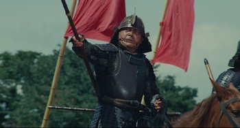 Movie still from “Ran” (1985), directed by Akira Kurosawa – An older man in armor holding a sword; Medium shot, Low angle