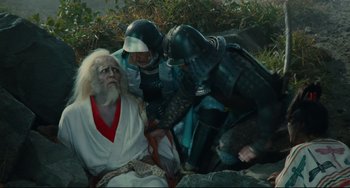 Movie still from “Ran” (1985), directed by Akira Kurosawa – A group of people dressed in costumes sitting next to each other on the ground; Medium shot, High angle