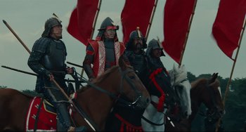 Movie still from “Ran” (1985), directed by Akira Kurosawa – A group of men riding on the backs of horses; Wide shot, Low angle