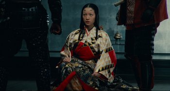 Movie still from “Ran” (1985), directed by Akira Kurosawa – A woman in a kimono sitting on the ground; Medium shot, High angle