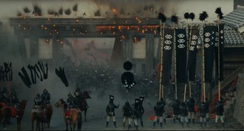 Movie still from “Ran” (1985), directed by Akira Kurosawa – A group of people in costumes on a street; Extreme Wide shot, High angle