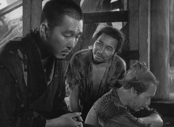 Movie still from “Rashomon” (1950), directed by Akira Kurosawa – A group of men sitting around a table; Medium shot, High angle
