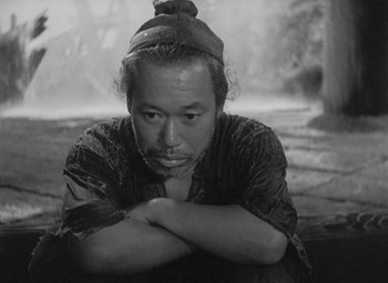 Movie still from “Rashomon” (1950), directed by Akira Kurosawa – Black and white photograph of a man with his arms crossed; Medium shot, Low angle