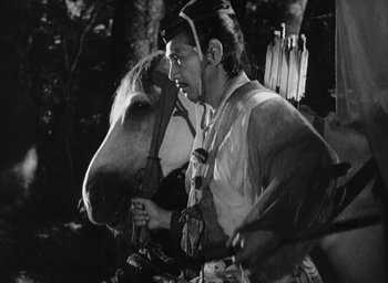 Movie still from “Rashomon” (1950), directed by Akira Kurosawa – A man in native american garb is holding a horse's bridle; Medium shot, Low angle