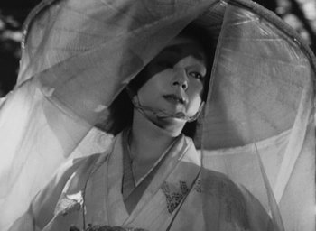 Movie still from “Rashomon” (1950), directed by Akira Kurosawa – A black and white photo of a woman with a parasol; Close Up shot, Low angle