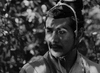 Movie still from “Rashomon” (1950), directed by Akira Kurosawa – A black and white photo of a man wearing a hat; Close Up shot, Low angle