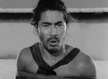 Movie still from “Rashomon” (1950), directed by Akira Kurosawa – Black and white photograph of a man tied to a rope; Close Up shot, High angle