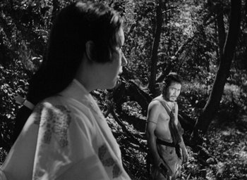 Movie still from “Rashomon” (1950), directed by Akira Kurosawa – A man and a woman standing next to each other in the woods; Medium shot, Over the shoulder angle