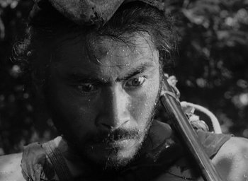 Movie still from “Rashomon” (1950), directed by Akira Kurosawa – Black and white photograph of a man holding a gun; Close Up shot, Low angle