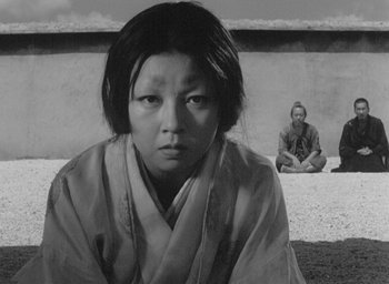 Movie still from “Rashomon” (1950), directed by Akira Kurosawa – A black and white photo of a woman in a kimono; Medium shot, High angle